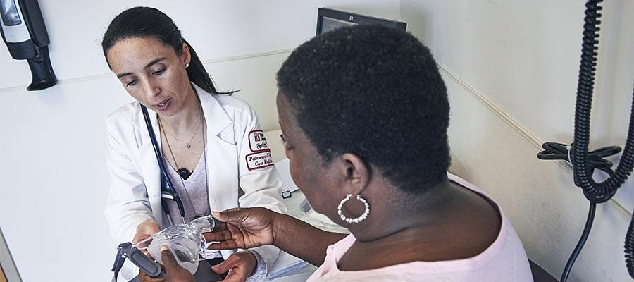 Dr. Maria Elena Vega-Sanchez showing a patient how to use a CPAP machine