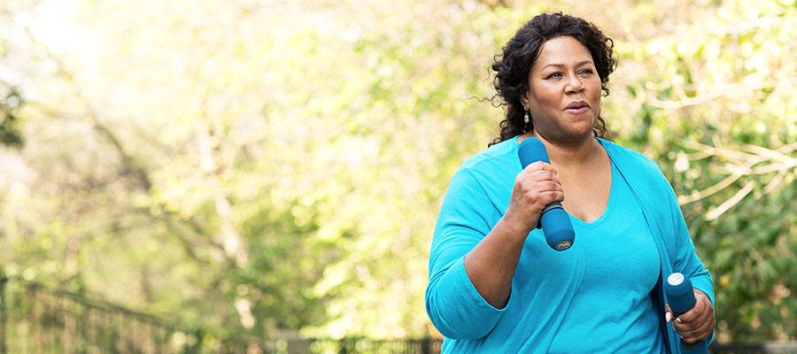 Woman walking outside while holding weights