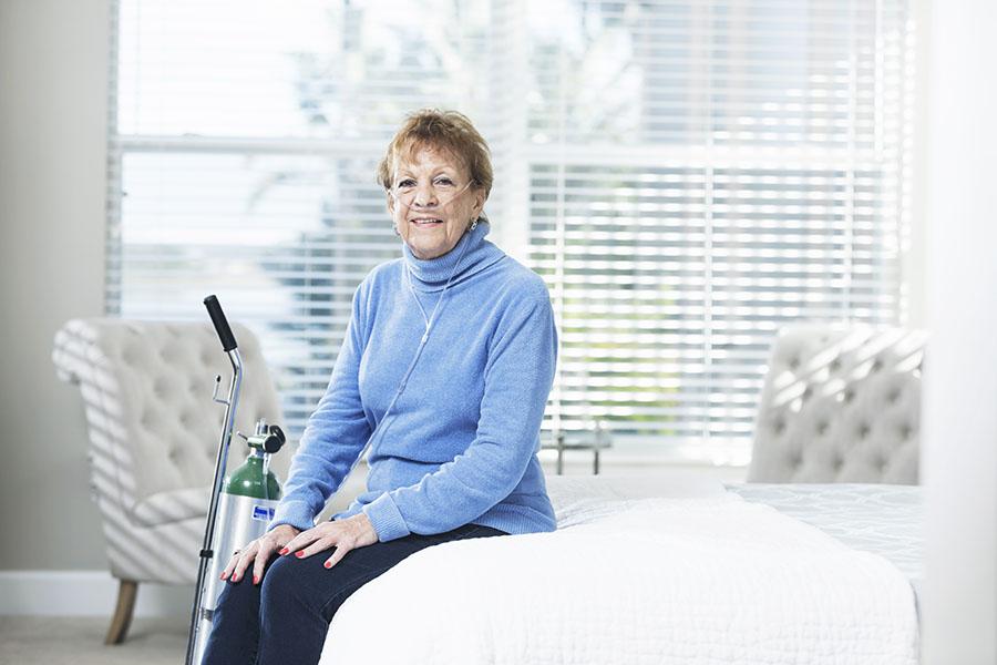 Woman sitting on bed with her oxygen equipment