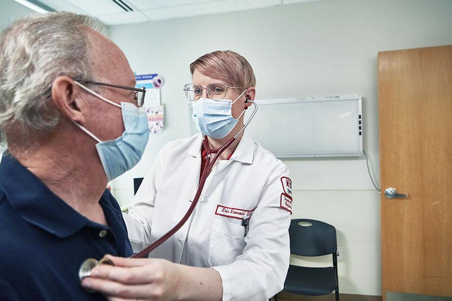 Dr. Erin Narewski using a stethoscope to check patient