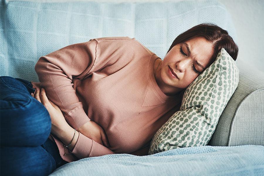 Young woman with stomach pain lying on the couch