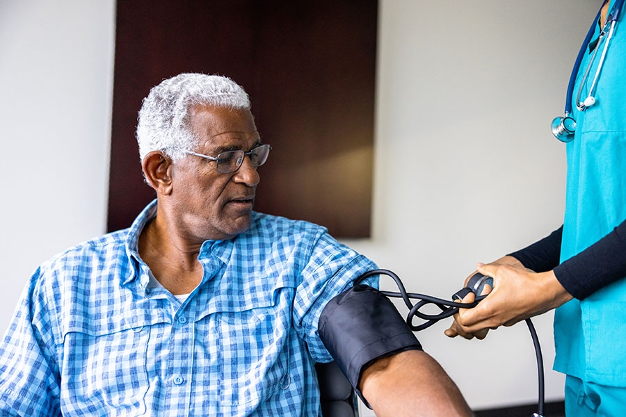 Nurse taking older man's blood pressure