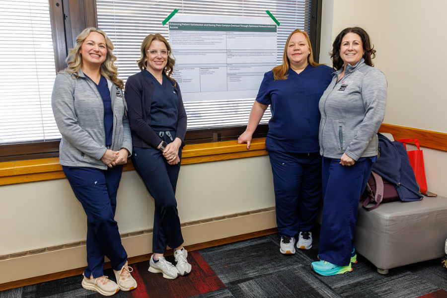 Tara DelGrippo, Jennie Gilliland, Erin Longstreth, and Sarah Porzig with the poster for their project, "Clear Pathways to Care: Optimizing Network Infusion Access for Patient Satisfaction and to Alleviate Main Campus Overload.