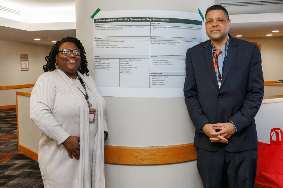 LaKeyya Grasty and Eric Morris with the poster for their project, "Patient Appointment Scheduling Discrepancies 7 Days Post-Discharge."
