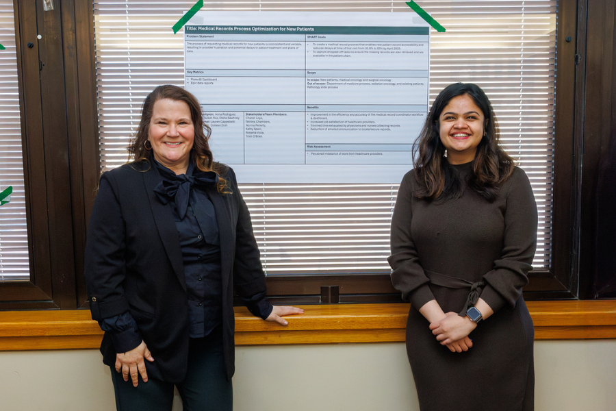 Susan Rux and Disha Sawhney with the poster for their project, "Medical Records Process Optimization for New Patients.