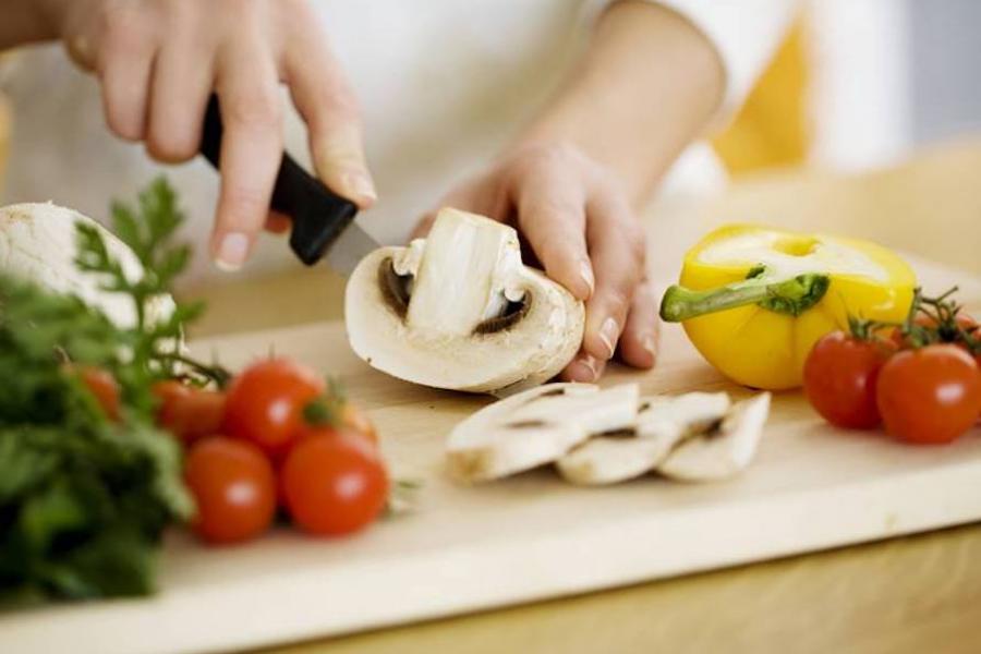 Person cutting vegetables on cutting board in kitchen