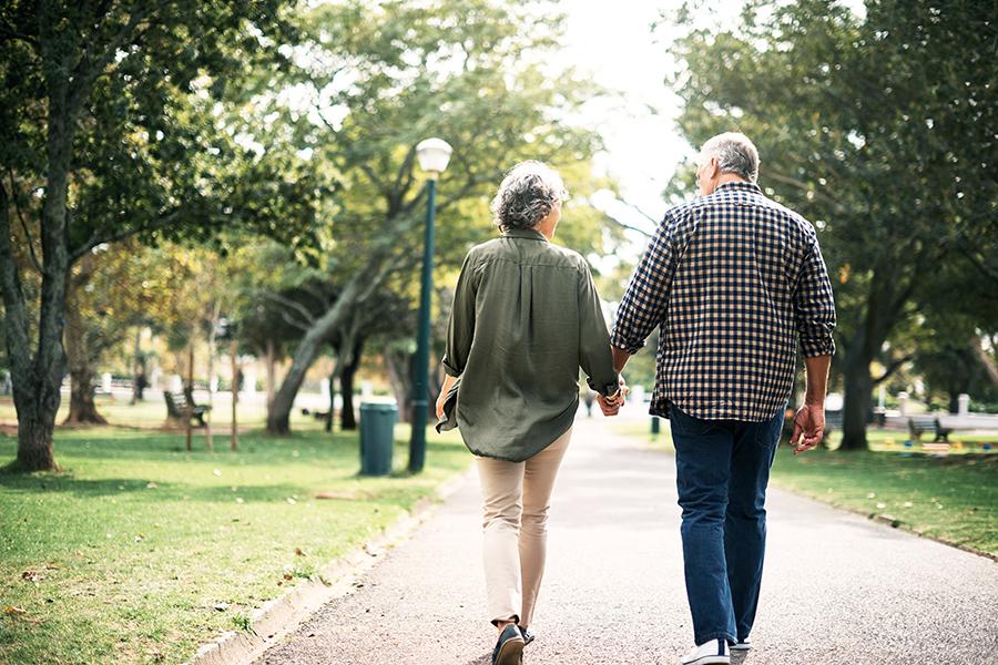 Older couple holding hands and walking outside