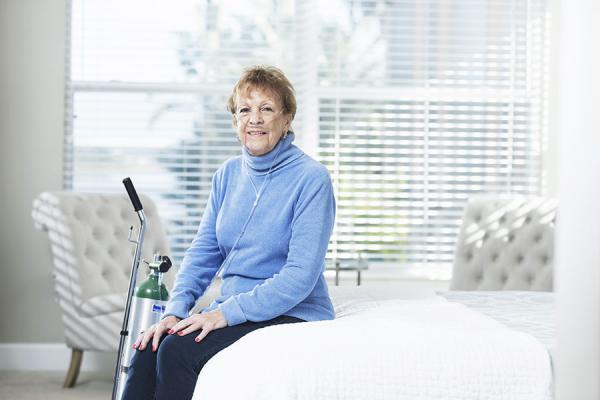 Woman sitting on bed with her oxygen equipment