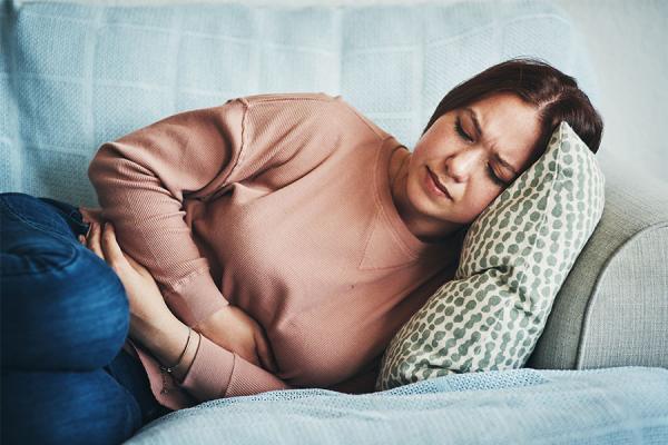 Young woman with stomach pain lying on the couch